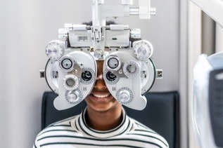 Optometrist in a consulting room with a phoropter and eye chart